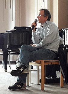 Foto des sitzenden Autors mit Mikrofon in der Hand
