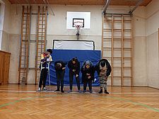 Foto von fünf Schüler/innen in einer Reihe  im Turnsaal, vier verbeugen sich, einer hat Krücken und verdeckt sein Gesicht.