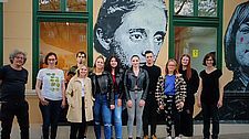 Foto von 11 Personen vor dem Bild von Christine Lavant auf der Fassade des Musil Hauses