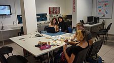 Foto von vier Schülerinnen bei der Arbeit mit dem Laptop und dem Spielbrett