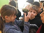 Foto von Schülerinnen und Schülern, ein Mädchen hält ein Glas mit Pflanzen und Tieren in der Hand